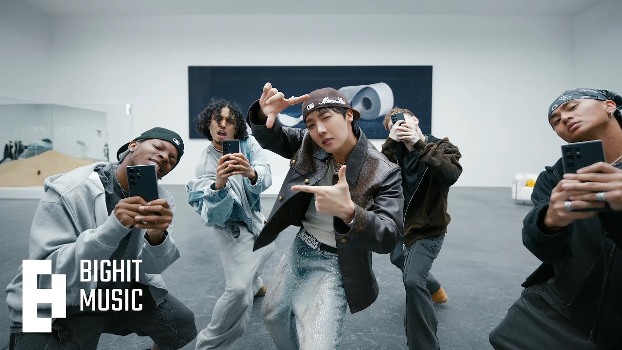 j-hope poses with dancers holding phones in a still from the official 'MONA LISA' music video